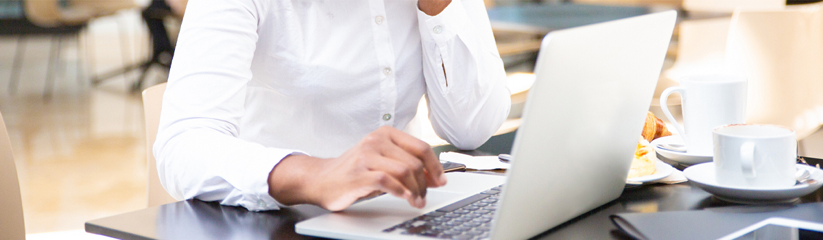 Woman working on laptop while eating breakfast