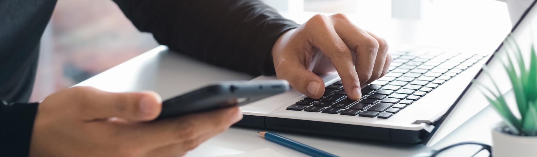 close up of someone setting alerts on their smartphone by a laptop