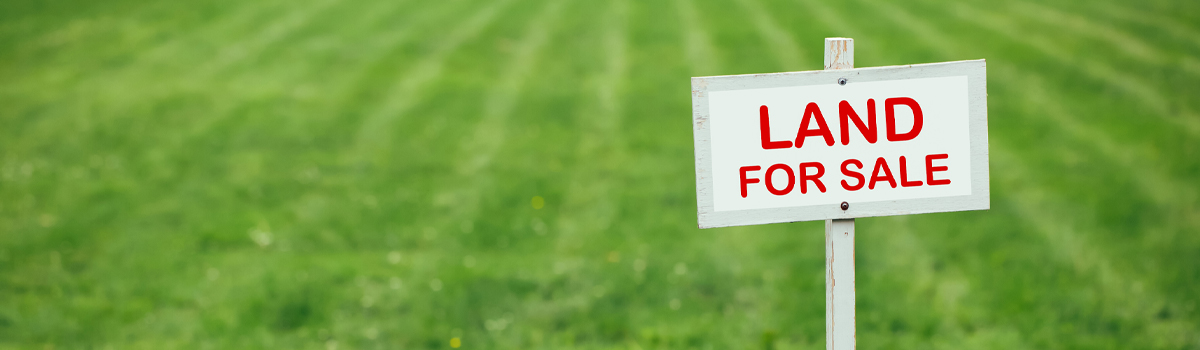 Green lawn with Land For Sale sign placed to the right 